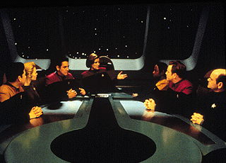 Janeway briefs her senior staff on the dangers of the Omega particle